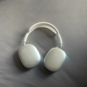 AirPods Max - Apple AirPods Max i silver. Trådlösa over-ear hörlurar med utmärkt ljudkvalitet och aktiv brusreducering. Synliga repor och slitage på kåporna, men öronkuddarna ser hela ut. Perfekt för musik, film och samtal. Levereras med avtagbara öronkuddar.