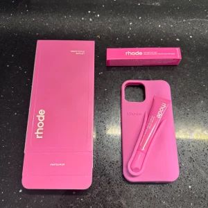 Rhode Lip Case för iPhone - Snyggt rosa Rhode Lip Case till iPhone, med plats för medföljande Peptide Lip Tint. Perfekt för dig som vill ha både skydd och läppbalsam nära till hands. Produkten ser oanvänd ut och levereras med originalförpackning.