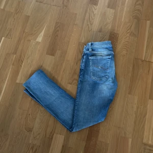 Jeans från Nudie - Säljer ett par ljus jeans från Nudie Jeans med klassisk vågig söm på bakfickan. Jeansen har normal midja, fem fickor och är tillverkade i mjuk bomullsdenim. Bra skick och storlek 29/32. Modell: Tight long John