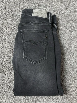 Replay svarta skinny jeans storlek 24 - Säljer ett par svarta skinny jeans från Replay i modellen JOI. Jeansen har klassisk femficksdesign, Replay-logga på bakfickan och snygga slitningar framtill. Materialet är stretchigt jeans för en tight passform och hög komfort.