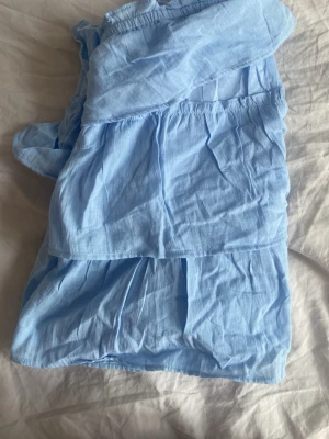 Ljusblå volangtop från Gina Tricot - Supersöt ljusblå topp från Gina Tricot med tunna axelband och flera lager volanger. Toppen är luftig och har en flowy passform, perfekt för varma dagar. Tillverkad i ett mjukt och lätt bomullstyg som känns skönt mot huden. 💙