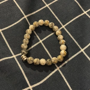 Ingen väst på bilderna - Bilderna visar ett armband med marmorerade pärlor i vitt, grått och guld. 