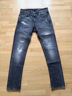 Replay Grover jeans  - Säljer ett par Replay Grover jeans i mörkgrå tvätt med snygga slitningar och lagade detaljer på benen. Modellen är rak/slim i passformen. Jeansen är i mycket bra skick då de endast är använda ett fåtal gånger. Storleken är W28 L32