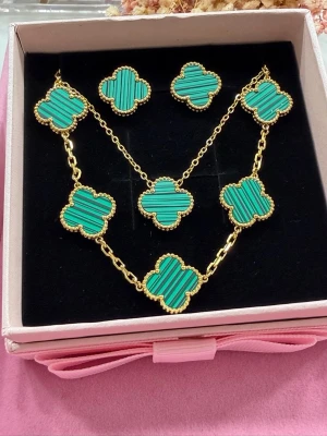 Klöver-set - Elegant och stilrent klöver-set i vacker grön färg som ger en lyxig och trendig känsla. Setet består av halsband, armband och örhängen, tillverkat i högkvalitativt rostfritt stål med exklusiv 18K guldplätering. Klöverdesignen i 15 mm ger ett tidlöst och feminint uttryck som passar både vardag och fest. Armbandet har justerbar längd på 19 cm till första hålet och 20 cm till det andra för optimal passform. Setet levereras i en elegant ask, perfekt som present.