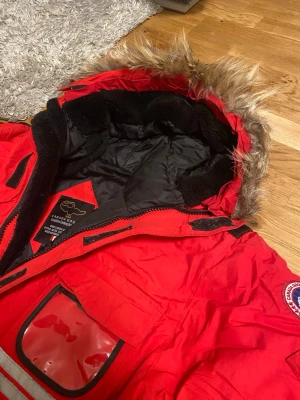 Röd Canada Goose Expedition Parkas - Säljer min Canada Goose Expedition Parka, helt äkta och i mycket gott skick. Den här modellen är känd för att vara extremt varm och tålig – perfekt för kalla vintrar.