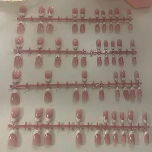 Rosa franska lösnaglar - Säljer ett set med rosa franska lösnaglar i olika storlekar. Naglarna har en klassisk fransk design med ljusrosa bas och vit tipp. Perfekt för att få snygga och välvårdade naglar snabbt. Materialet är plast och naglarna kommer på ställ för enkel applicering.
