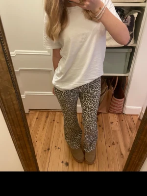 Leopardmönstrade bootcut jeans  - Säljer ett par snygga bootcut byxor med leopardmönster i svart, grått och vitt. Byxorna har en skön passform och är perfekta för dig som vill sticka ut. Materialet känns mjukt och stretchigt, vilket gör dem riktigt bekväma att bära hela dagen.