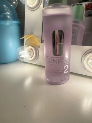 Clinique Clarifying Lotion 2 400ml - Lila flaska med grön kork från Clinique, innehåller 400 ml Clarifying Lotion 2. Denna toner är speciellt framtagen för torr till kombinerad hud och används som exfolierande steg i hudvårdsrutinen. Snygg design med silverdetaljer på etiketten. Öppnad och knappt använd men som ny. 