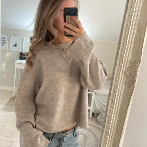 Beige stickad tröja med loose fit - Mysig beige stickad tröja med avslappnad passform och långa ärmar. Tröjan har en enkel rund halsringning och är perfekt för lager-på-lager. Materialet är mjukt och ger en chill vibe till outfiten.