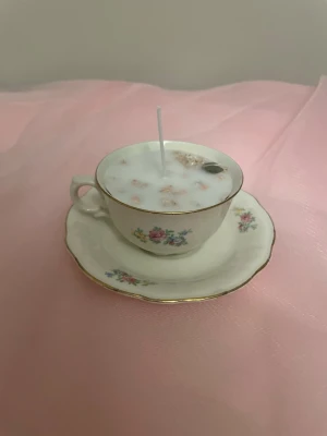 Doftljus i vanilj i en kräm vit färgad tekopp med blommor - Det här ljuset är gjort av återanvändbara material. Tekoppen är köpt secondhand och stearinet är från kyrkor som tänkte slänga det. Det här ljuset har en svag doft utav vanilj, så känsliga även kan använda det. Det här ljuset har även torkade blommor på som dekoration.