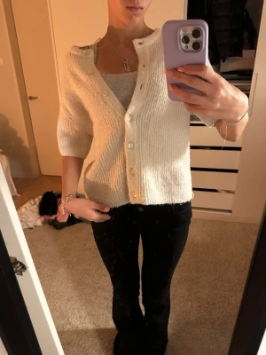 vit kofta från Gina Tricot i ullmix - mysig vit kofta från Gina Tricot i ullblandning. koftan har ribbad struktur, knappar framtill och halvlånga ärmar. perfekt att slänga över ett linne eller t-shirt för en chill och stilren look. köpte den i mars, och inte använt så ofta - men tvättat en gång men syns inte att den är ytterst lite nopprig. passar till vilken outfit som helst! 