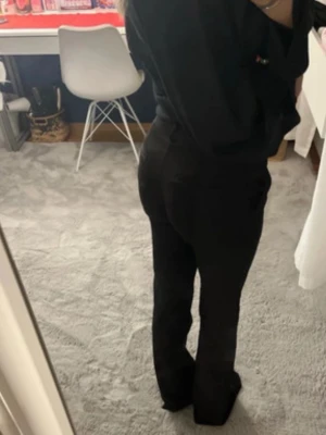 Svarta kostymbyxor bootcut byxor med midja - Säljer ett par svarta kostymbyxor bootcut byxor med snygg passform och midja. Byxorna har klassisk look med knapp och dragkedja framtill. Perfekta till en enkel topp eller hoodie. Materialet känns mjukt och följsamt, vilket gör dem riktigt bekväma.