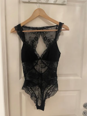 Svart spetsbody från H&M, storlek S - Säljer en svart body från H&M i storlek S. Bodyn är helt i spets med blommigt mönster, HELT OANVÄND skulle ha på nyårsfest men blev inställd så har alldrig blivit använd bara blivit testad över kostymbyxor 