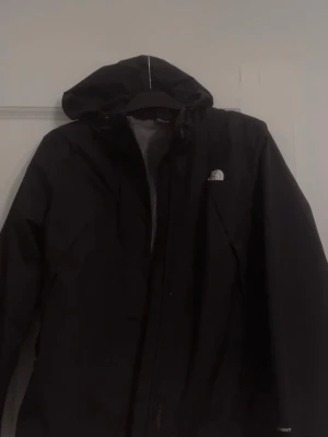The North Face vindjacka  - Vindjacka från The North Face i mycket bra skick. Använd ett par gånger men utan defekter. Kan finnas någon liten smink fläck vid kragen, men går isåfall bort enkelt. Storlek M, men är mer som en S/XS. Tycker den är för liten på mig som normalt sätt är en S. Är 175 lång och har långa armar. Modellen framhäver ens midja och den går att spänna in längst ner. Luvan går också att justera.