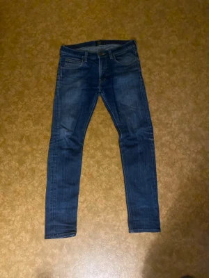 Mörkblå skinny jeans från Lee - Snygga mörkblå jeans från Lee med klassisk femficksdesign och skinny passform. Jeansen har en normal midja och är gjorda i mjukt denim-material med lätt tvättade detaljer. Perfekta för dig som gillar en smal siluett och stilren look.
