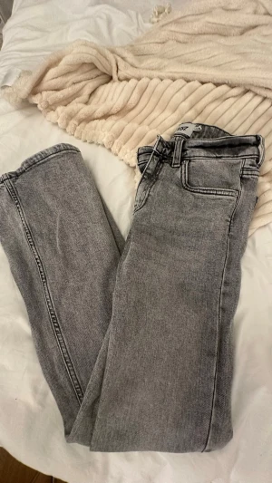 lager 157 grå jeans XS short - Säljer ett par grå Lager 157 jeans i storlek XS short. Klassisk femficksmodell med raka ben och normal passform. Jeansen har en snygg tvättad grå färg och är tillverkade i slitstarkt bomullsmaterial. Perfekta för dig som gillar tidlös stil och vill ha ett par jeans med cool vibe.