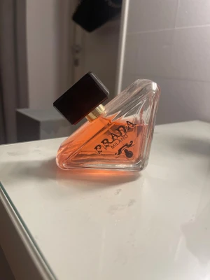 Prada Milano unik parfymflaska - Snygg och modern parfym från Prada Milano i en unik, geometrisk flaska med orange innehåll. Perfekt för dig som vill sticka ut med en exklusiv accessoar på hyllan. Märket signalerar lyx och trendkänsla.