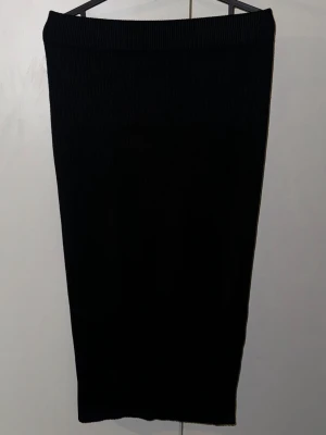 Svart ribbad långkjol från Even&Odd - Säljer en svart långkjol från Even&Odd med ribbad struktur. Kjolen har en enkel och stilren design med rak passform och elastisk midja. Perfekt för dig som gillar minimalistisk stil och vill ha något som är lätt att matcha med olika toppar.