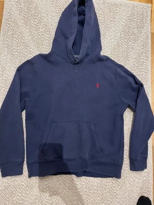 Raulph lauren hoodie - Dethär är en marinblå Raulph lauren hoodie med den klassiska röda hästen. Tröjan är i mycket fint skick och har inte en enda skada, passar perfekt för dig som vill ha en lite snyggare och modernare stil.