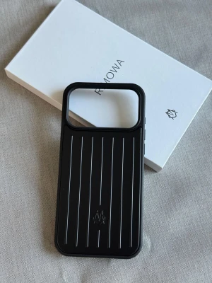 Rimowa iPhone 17 Pro Case - Elegant och robust Rimowa-skal för iPhone 17 Pro i svart med ikoniska räfflade linjer. Ger utmärkt skydd mot repor och stötar, samtidigt som det behåller en stilren design. Skalet är i nyskick utan synligt slitage eller defekter. Köptes nyligen på NK för 1750kr. Pris går att diskuteras. Finns att hämta på Östermalm