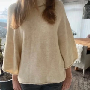 Populär stickad polotröja/poncho från zara  - Säljer en beige/vit stickad polotröja med breda, trekvartsärmar och hög krage. Tröjan har en loose passform och är tillverkade i mjukt material som ger en chill och avslappnad vibe. Perfekt för lager-på-lager under höst och vinter.