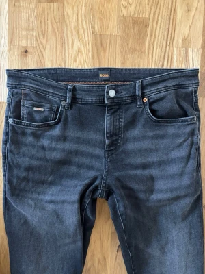 Mörkblå jeans från BOSS - Snygga mörkblå jeans från BOSS med klassisk femficksdesign och diskreta kontrastsömmar. Jeansen har rak passform och är tillverkade i mjukt denimtyg med en lätt tvättad look. Perfekt för dig som gillar stilrena och tidlösa jeans.