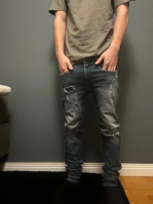 Replay Anbass blå skinny jeans - Säljer ett par Replay Anbass jeans i blå tvätt med slitningar och trasiga detaljer på framsidan. Skinny fit med låg midja. Jeansen har en snygg faded effekt och är gjorda i stretchig bomull för skön passform. Skick 8/10 