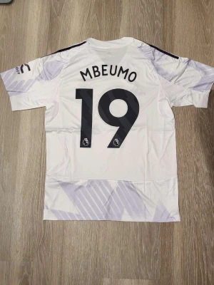 Vit Manchester United fotbollströja M med Mbeumo - Säljer en vit Manchester United fotbollströja med Mbeumo på ryggen. Helt ny och inte använd. Pris kan diskuteras vid snabb affär och skickar snabbt. 