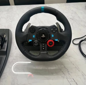 Logitech G29 Racing Wheel & Pedals - Logitech G29 ratt, pedaler och växelspak för PlayStation och PC. Perfekt för racing- och bilspel, med realistisk force feedback och slitstark konstruktion. Alla delar ser ut att vara i gott skick utan synligt slitage. Strömkabel medföljer.