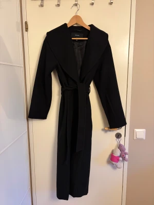 Lång kappa - En lång svart kappa från vero moda med slits där bak och den är oanvänd. Nypris 849