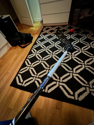 Unihoc Carbskin Slim 26 96 cm - Säljer en Unihoc Carbskin Slim innebandyklubba med svart och vit design. Skaftet är tillverkat i kolfiber och har en slim form för bättre grepp. Bladet är svart och har ett öppet rutmönster för lätt bollkontroll. Perfekt för dig som vill ha snabb och smidig spelkänsla.