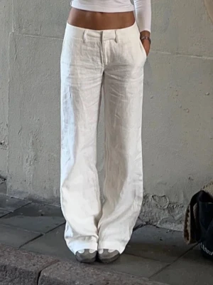 Alobha Label classy linen pants - Snygga vita linnebyxor med breda ben och låg midja. Byxorna har klassiska fickor och hällor för bälte, vilket gör dem perfekta för en chill och trendig look. Materialet är linne som ger en luftig och fräsch känsla. 