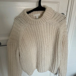 Beige stickad tröja med polokrage - Säljer en chunky beige stickad tröja från H&M med bred polokrage och grov ribbstickning. Tröjan har lång ärm och en oversized, mysig passform som är perfekt för kyliga dagar.