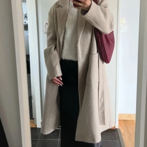 Beige kappa med bälte och stora fickor - Stilren beige kappa från Gina Tricot med klassisk krage, stora framfickor och bälte i midjan. Lång modell med rak passform. Perfekt för lager-på-lager och snygg till både jeans och kostymbyxor. Lite nopprig på vissa ställen som den lätt blir men annars i bra skick 🤗passar även mig som vanligtvis har strl S. Köpt för ca 900 kr 