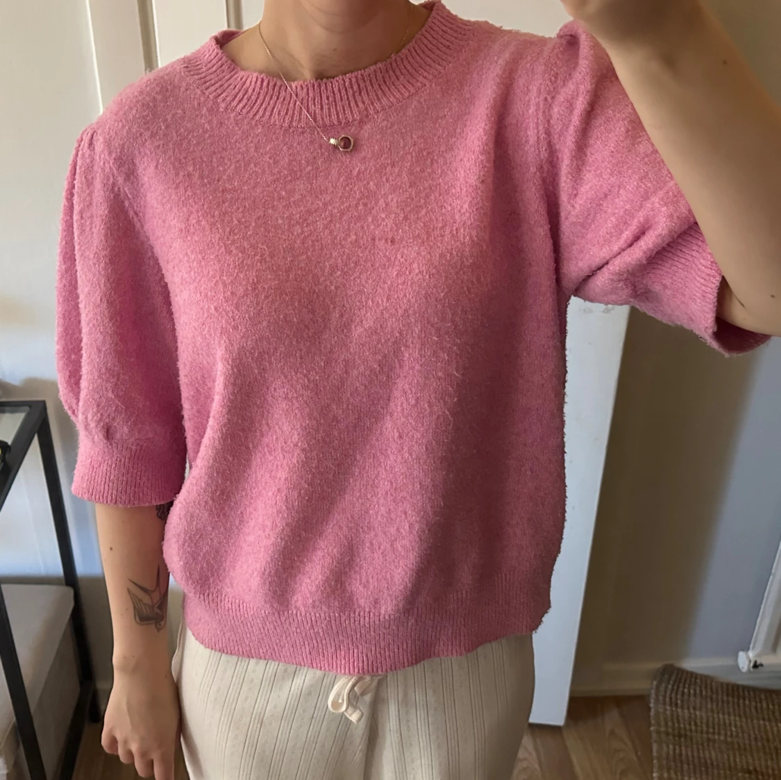 En rosa stickad tröja med puff ärm