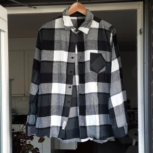 Rutig svartvit (grön) skjorta med ficka - Säljer en snygg rutig skjorta i svart, grått och vitt med klassisk krage och bröstficka. Skjortan har knäppning framtill och långa ärmar. (Är även lite mörkgrön, men det syns ej på bilderna) Öppen för prutning