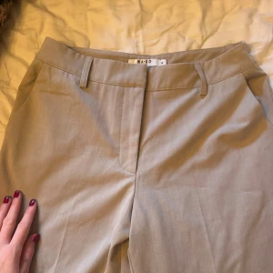 Beiga kostymbyxor från NA-KD! - Snygga beiga kostymbyxor från NA-KD med klassisk rak passform och hällor för bälte. Byxorna har diskreta fickor i sidorna. Endast använda ett fåtal gånger så väldigt fint skick!🤎