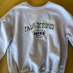 Ljuslila Palm Springs sweatshirt - Superfin ljuslila sweatshirt med tryck 'Palm Springs Coachella Valley Est 1986' framtill. 