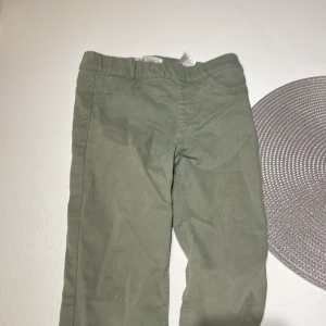 Gröna byxor från H&M, stl 128 - Snygga gröna byxor från H&M i storlek 128. Byxorna har klassisk femficksdesign och är tillverkade i en mjuk bomullsblandning med lite stretch för skön passform. Perfekta för dig som gillar en enkel och stilren look.
