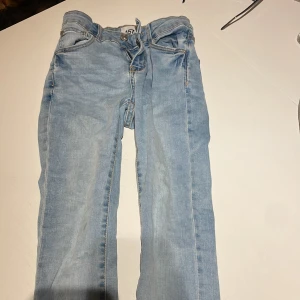 Ljusblå jeans från 157, strl 140 - Säljer ett par ljusblå jeans från 157 i modellen Skippy, storlek 140. Klassisk femficksmodell med dragkedja och knapp, samt snörning i midjan. Jeansen har raka ben och är tillverkade i mjukt denimtyg för en skön känsla.
