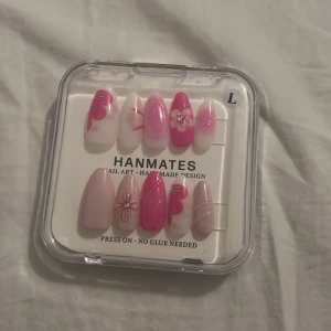 Press-on naglar Hanmates Pink Jelly Flower - Säljer ett set med press-on naglar i storlek L från Hanmates. Naglarna har coola designer i rosa, nude och vitt med blommor, swirl-mönster och glansig finish. Materialet är plast och paketet innehåller även en liten nagelfil och klisterflikar. Ingen lim behövs, superenkelt att använda!
