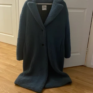 Mörkblå teddyjacka från Zara, L - Säljer en lång, mörkblå teddyjacka från Zara i storlek L. Jackan har oversized passform, stora slag och stängs med knappar framtill. Den är gjord i mjukt teddy-material och har en clean look utan synliga detaljer. Perfekt för kalla dagar. Priset är inte hugget i sten