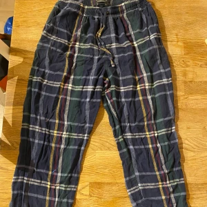 Rutig pyjamasbyxa från Dressmann L/XL - Mysiga pyjamasbyxor från Dressmann i storlek L/XL. Mörkblå botten med rutigt mönster i grönt, gult, rött och vitt. Har 3 fläckar på sig men inget som direkt syns när man väl har på sig dom med har med dom så man är redo att dom finns där. 