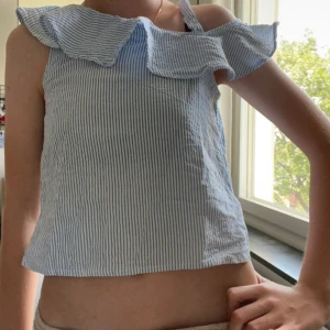 Blåvit randig linnetopp med volang - Säljer en söt blåvit randig linnetopp med bred volang längs axlarna och axelband. Den är i barn storlek💗