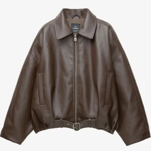 Brun skinnjacka från Pull&Bear - Säljer en brun skinnjacka från Pull&Bear med oversized passform. Jackan har klassisk krage, dragkedja framtill och bälte i midjan för extra edge. Har aldrig använt jackan pga fel storlek, prislapp finns på.