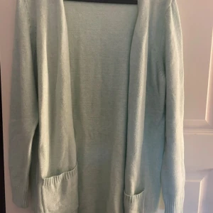 Ljusgrön kofta från ONLY - Mysig ljusgrön kofta från ONLY med långa ärmar och två praktiska fickor framtill. Koftan är stickad och har ribbade muddar vid ärmslut och nederkant. Perfekt att slänga på sig när det är lite kyligt ute.