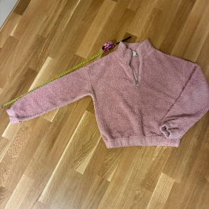 Rosa teddytröja från H&M med half zip - Mysig teddytröja från H&M i en ljusrosa färg. Tröjan har en hög krage och en half zip-dragkedja framtill. Tillverkad i fluffig polyester som ger en skön och varm känsla. Perfekt för kyliga dagar och chill outfits. I använt skick! Från djur-rök och parfymfritt hem. 