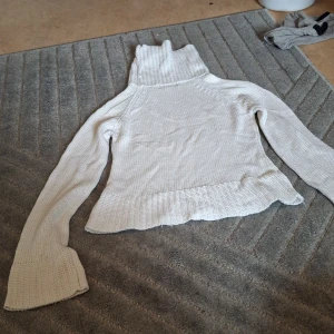 Vit stickad polotröja från ONLY - Säljer en vit stickad polotröja från ONLY i storlek L. Tröjan har en hög polokrage, långa ärmar och breda muddar vid ärmslut och nederkant. Perfekt för kyliga dagar och superenkel att styla till jeans eller kjol.