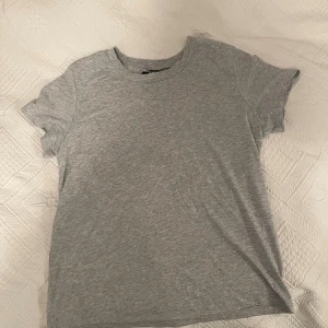 Grå basic t-shirt  - Enkel och stilren grå t-shirt i mjukt material . Klassisk rund halsringning och korta ärmar. Perfekt basplagg som passar till allt 