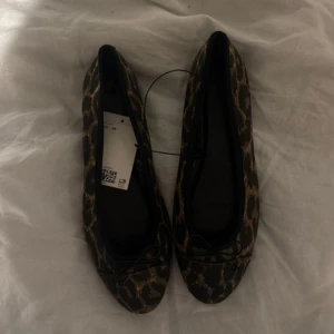 Leopardmönstrade ballerinaskor H&M - Snygga ballerinaskor från H&M i leopardmönster med svarta och bruna toner.  Aldrig använda!!!